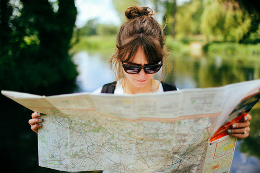 Woman wearing sunglasses, being in nature and looking at a map